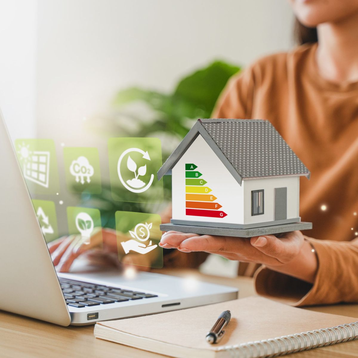 Mano sujetando maqueta de casa con iconos de valores de ahorro energético