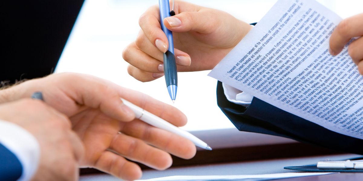 manos sujetando boli y enseñando parte de un escrito en papel