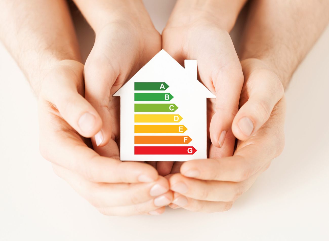 manos sujetando maqueta de casa con iconos ahorro energético